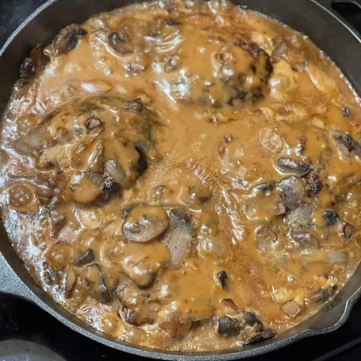 Hamburger steak smothered in brown gravy with mushrooms and onions